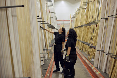 Multiracial female colleagues discussing over planks in lumber industry