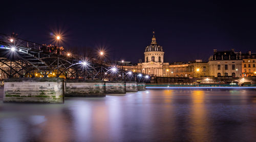 Illuminated buildings by river at night