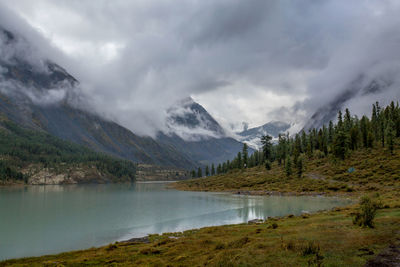 Scenic view of lake and mountains against cloudy sky