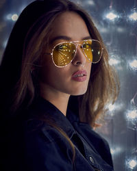 Portrait of young woman in sunglasses at night