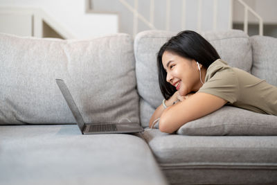 Portrait of young woman sitting on sofa at home