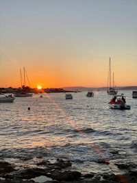 Sailboats in sea against clear sky during sunset