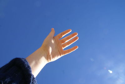 Cropped image of woman hand against blue sky