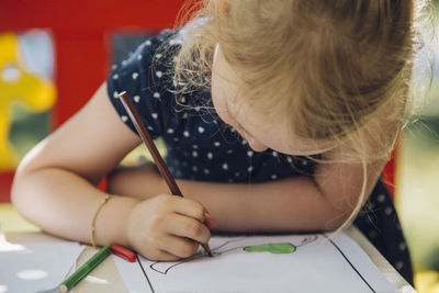 Girl coloring paper on table