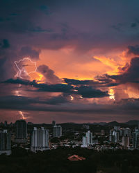 Scenic view of city against dramatic sky during sunset