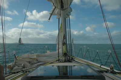 Sailboat on sea against cloudy sky