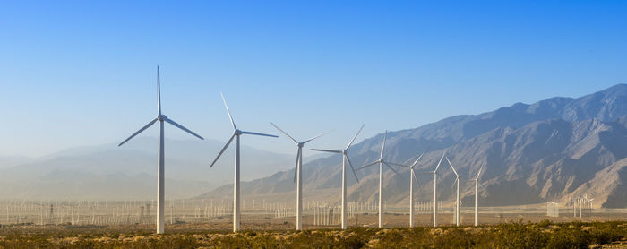 Wind turbines on field against clear sky