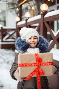 Portrait of smiling girl holding gift outdoors