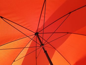 Low angle view of red umbrella against orange sky