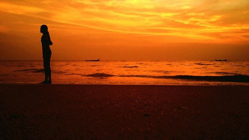 Silhouette person on beach against sky during sunset