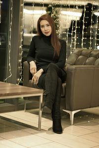 Full length portrait of woman sitting on armchair