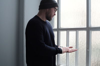 Sad man looking away while standing by window