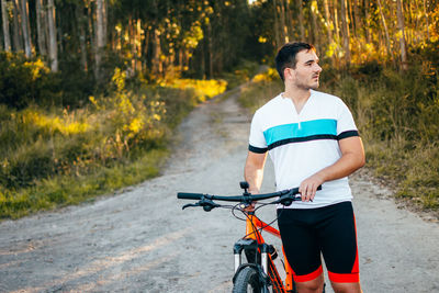 Sportswear young man pushing bicycle in the mountains