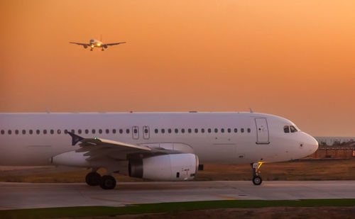 Airplane flying in sky at sunset