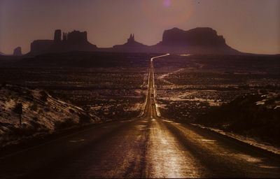 Road by illuminated mountain against sky at night