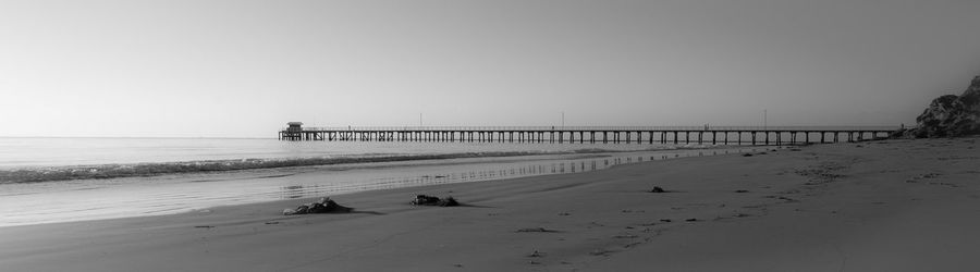 Scenic view of beach and pier against clear sky