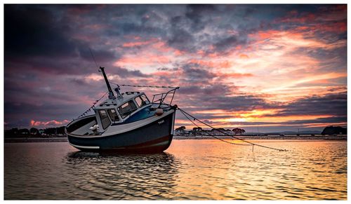 Ship moored on sea against sky during sunset