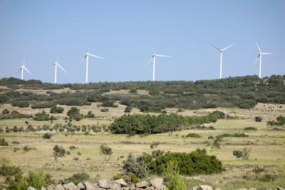 Windmills on field against sky