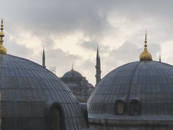 View of mosque against cloudy sky in city