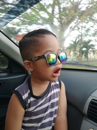 Shocked boy wearing sunglasses in car