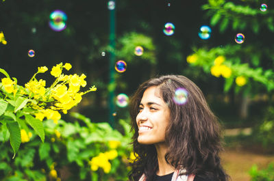 Close-up of smiling young woman with bubbles in park