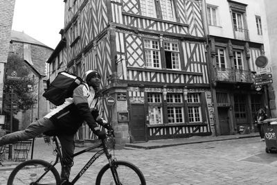 Man riding bicycle on street against buildings in city