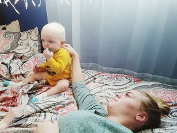 Mother touching son while lying on bed at home