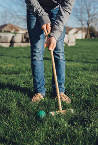 Cropped image of teen boy hitting croquet ball with a mallet.