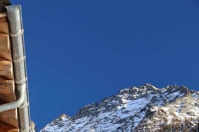 Low angle view of snowcapped mountain against clear blue sky