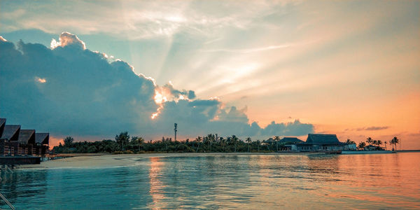 Panoramic view of sea and buildings against sky during sunset