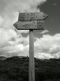 Low angle view of signboard on landscape against sky