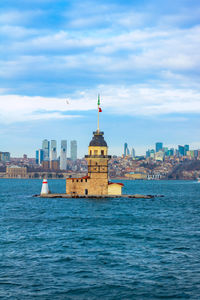 View of buildings in sea against cloudy sky