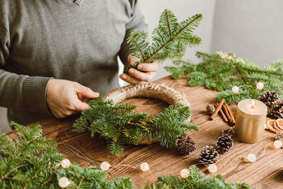 A man at home makes a christmas wreath from fresh spruce branches. decorating your home 