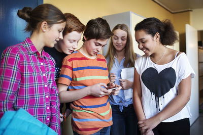 High school students using mobile phone in locker room