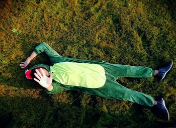 High angle view of man in green mascot lying on land