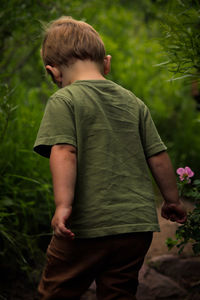 Rear view of boy standing against plants