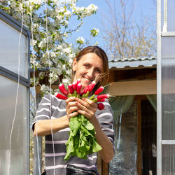 Happy girl holding flower standing against plants