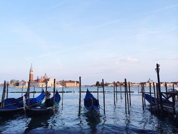 Gondolas moored on grand canal against blue sky