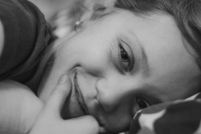 Close-up portrait of girl smiling while lying on bed