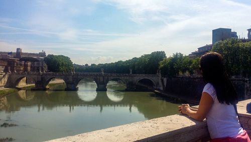 Rear view of woman standing on bridge over river