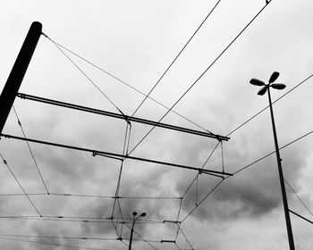 Low angle view of birds on cables against sky