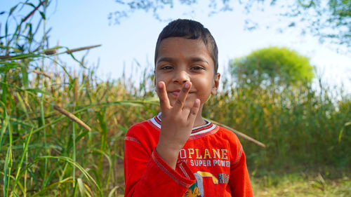 Indian adorable little kid in woollen clothes and showing victory sign in front of camera.