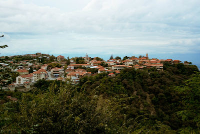 High angle view of houses by sea against cloudy sky