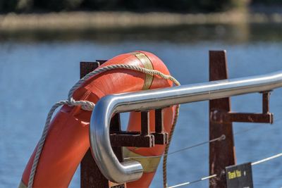 Close-up of life belt hanging on railing by lake