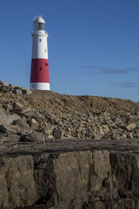 Low angle view of lighthouse by building against sky