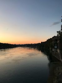 Scenic view of river by buildings against sky during sunset