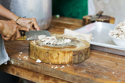 Cropped hands of butcher chopping meat