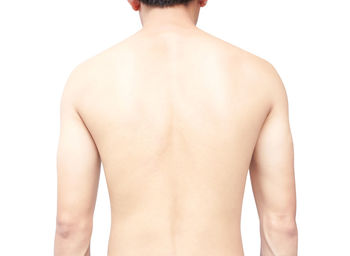 Rear view of shirtless man standing against white background