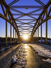 Snowy road on bridge facing sunset