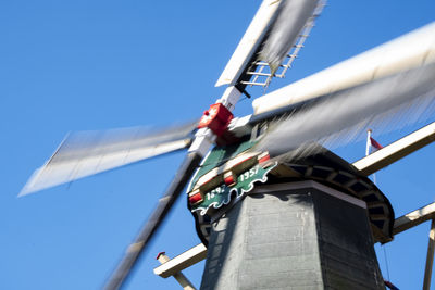 Low angle view of windmill against clear blue sky